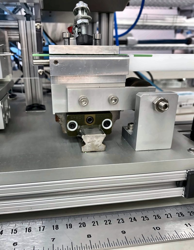 Machined aluminum slide on a linear guide rail, with a steel rule in front for scale